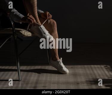 Frau zog neue weiße Leder-Sneakers an Stockfoto