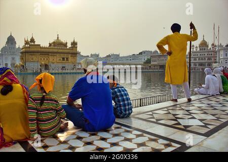 Amritsar, Indien - 06. November 2016: Ein nicht identifizierter Besucher und Pilger, der am Teich sitzt, und ein männlicher Sicherheitsmann, der dem Sikh-Famou zugewandt ist Stockfoto