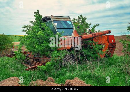 Alte verlassene Rostbewachsener kombinieren mit Büschen auf dem Feld Stockfoto