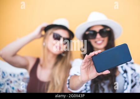 Zwei Mädchen genießen Sightseeing im Freien. Wunderschöne weibliche Touristen, die die Stadt erkunden und Selfie machen Stockfoto
