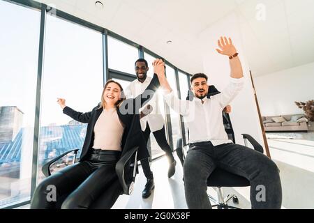Glückliche, multirassische IT-Mitarbeiter sitzen im Büro Stockfoto