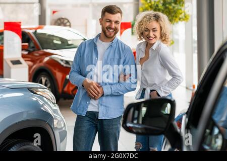 Das junge Paar geht durch den Autohändler auf der Suche nach einem neuen Auto Stockfoto