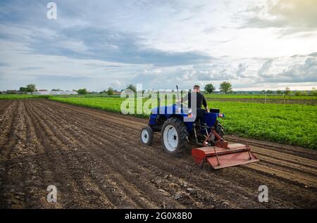 Landwirt auf Traktor bewirtschaftet Ackerfeld. Boden fräsen, Boden zerbröckeln, bevor Reihen geschnitten werden. Landwirtschaft, Landwirtschaft. Lockere Oberfläche, Landbewirtschaftung Stockfoto