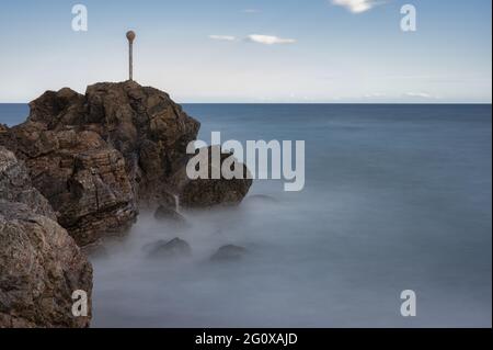 Schöne Aufnahme eines nebligen Meeres vor einem Steinhügel Stockfoto