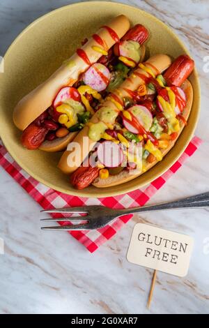 Ausgefallene Chili-Hunde mit Radieschen Senf Ketchup und grün gekrönt Soße auf glutenfreien Brötchen Stockfoto