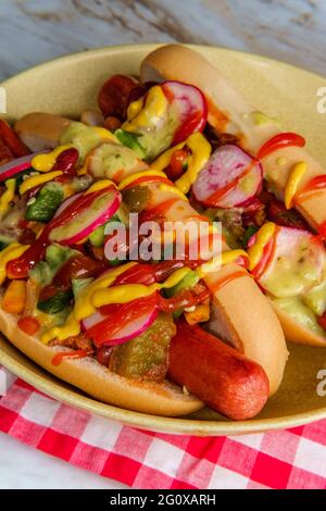 Ausgefallene Chili-Hunde mit Radieschen Senf Ketchup und grün gekrönt Soße auf glutenfreien Brötchen Stockfoto