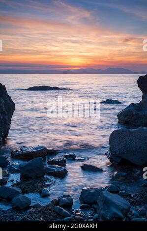 Ein farbenfroher Sonnenuntergang über dem Meer von der felsigen Küste in Dunure in South Ayrshire, Schottland. Stockfoto