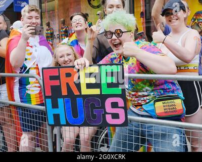Nachtschwärmer halten ein Schild mit „Free Umarmungen“ hoch, während sie die Jubilee Pride Parade in London beobachten Stockfoto