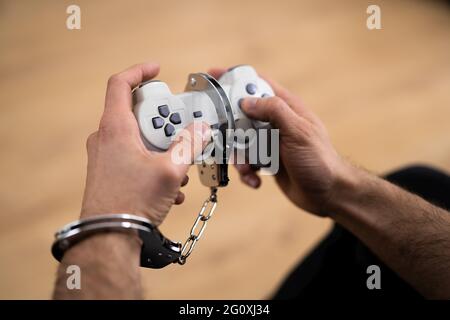 Sucht Nach Videospielen. Handschellen und Gamepad oder Joystick Stockfoto