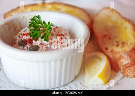 Ein weißes Ramekin mit frischem Meeresfrüchtedip und Knoblauchtoast Stockfoto