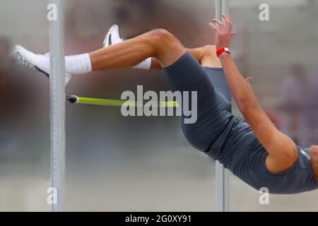 Ein hoher Jumper räumt bei einem Leichtathletik-Wettkampf die Messlatte ein. Stockfoto