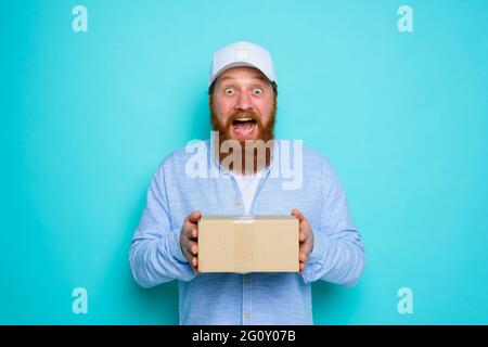 Kurier mit Karton in der Hand ist über etwas überrascht Stockfoto
