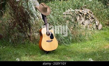 Eine akustische Gitarre, Cowboy-Hut und die Natur Stockfoto