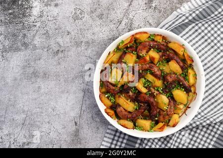 Im Ofen gebackene Hühnerhälse mit Kartoffeln in einer weißen Backform auf dunkelgrauem Hintergrund. Draufsicht, flach liegend Stockfoto