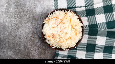 Hausgemachtes Sauerkraut mit Karotte in einer Schüssel auf dunklem Grund. Vegane Küche. Draufsicht, flach liegend Stockfoto