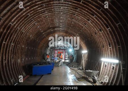 03. Juni 2021, Hamburg: Im Westrohr des Alten Elbtunnels arbeiten Arbeiter mit Atemmasken und Schutzanzügen. Es wird wahrscheinlich noch fünf Jahre dauern, bis Hamburg den Alten Elbtunnel wieder vollständig in Besitz nehmen kann. Nach der Wiedereröffnung der Oströhre vor zwei Jahren sollte dann auch die Weströhre, die seit 2019 repariert wird, fertig sein. Die Gesamtkosten für das jahrzehntelange Renovierungsprojekt sollten sich bis dahin auf 114 Millionen Euro belaufen, wie Finanzsenator Dressel bei einem Rundgang durch die Bauarbeiten sagte. (To dpa 'Renovierung des Alten Elbtunnels: West Tub Stockfoto