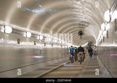 03. Juni 2021, Hamburg: Passanten wandern oder radeln durch die Oströhre des Alten Elbtunnels. Es wird wahrscheinlich noch fünf Jahre dauern, bis Hamburg den Alten Elbtunnel wieder vollständig in Besitz nehmen kann. Nach der Wiedereröffnung der Oströhre vor zwei Jahren sollte dann auch die Weströhre, die seit 2019 repariert wird, fertig sein. Die Gesamtkosten für das jahrzehntelange Renovierungsprojekt sollten sich bis dahin auf 114 Millionen Euro belaufen, wie Finanzsenator Dressel bei einem Rundgang durch die Bauarbeiten sagte. (An dpa 'Renovierung des Alten Elbtunnels: Weströhre soll 2026 eröffnet werden') Stockfoto