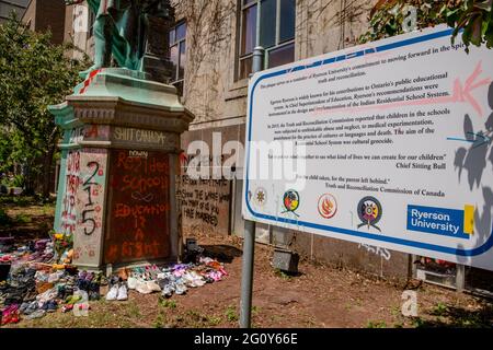 Toronto, Kanada. Juni 2021. Die Statue wurde in roter Farbe übergossen.215 Schuhe wurden um die Statue von Egerton Ryerson auf dem Campus der Ryerson University als Gedenkstätte gelegt und nach der Entdeckung von 215 Leichen von Studenten aus Wohnschulen in Kamloops, British Columbia, an einem Massengrab verwüstet. Egerton Ryerson war ein ursprünglicher Architekt des Wohnschulsystems. Kredit: SOPA Images Limited/Alamy Live Nachrichten Stockfoto