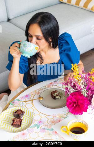 Junge Brünette Frau genießt es, Süßigkeiten mit Kaffee zu essen Stockfoto