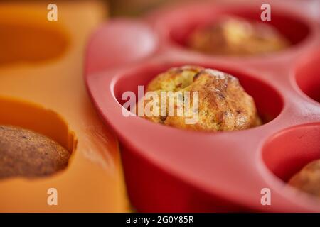 Gebackene Muffins mit sonnengetrockneten Tomaten in Silikonform nach dem Backen Stockfoto