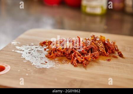 Sonnengetrocknete Tomaten auf Holzbrett, fertig für die Herstellung von Muffins mit sonnengetrockneten Tomaten Stockfoto