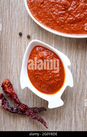 Indisches Essen - Goan Fisch-Urcreme oder einfache rote Kokosnuss Fisch-Urcreme-Masala. Serviert in der fischförmigen Schüssel. Zutaten im Hintergrund mit Platz für Kopien. Stockfoto