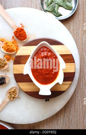 Indisches Essen - Goan Fisch-Urcreme oder einfache rote Kokosnuss Fisch-Urcreme-Masala. Serviert in der fischförmigen Schüssel. Zutaten im Hintergrund mit Platz für Kopien. Stockfoto