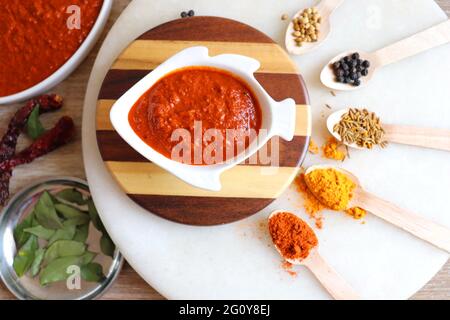 Indisches Essen - Goan Fisch-Urcreme oder einfache rote Kokosnuss Fisch-Urcreme-Masala. Serviert in der fischförmigen Schüssel. Zutaten im Hintergrund mit Platz für Kopien. Stockfoto