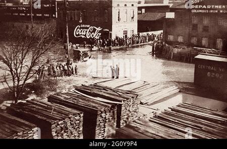 Oldtimer, die durch überflutete Straßen in Columbus, Georgia, fahren, während die Zuschauer von trockenem Boden aus zusehen. Der Chattahoochee River, der an Uptown Columbus entlang fließt, überflutete Mitte Februar 1900 seine Ufer. Stockfoto