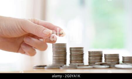 Frau legte Münzen zu Stapel von Münzen Stockfoto