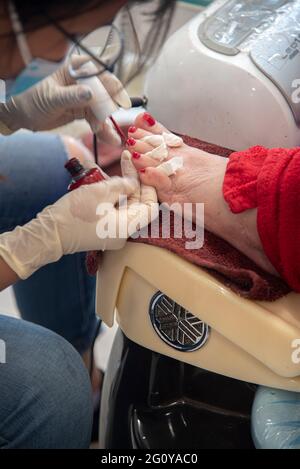 Eine 84-jährige, hispanische Frau, die in ihrem lokalen Schönheitssalon eine Kombination aus Pediküre und Maniküre bekommt. Stockfoto