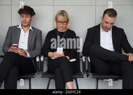 Menschen sitzen warten auf ein Vorstellungsgespräch und die Nutzung von sozialen Medien Anwendung auf Handy. Human Resources recruitment Konzept Stockfoto