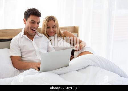Kaukasisches Paar sucht billige Flugtickets und Hotel im Web online mit Laptop auf dem Bett, Vorbereitung und finden erstaunliche Unterkünfte für Urlaub Konz Stockfoto