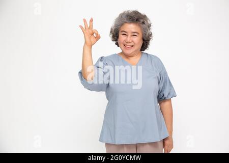 Porträt einer glücklichen Senior asiatische Frau Geste oder zeigt die Hand ok und Blick auf die Kamera isoliert auf weißem Hintergrund, ältere Frau Gefühl positiv und Stockfoto