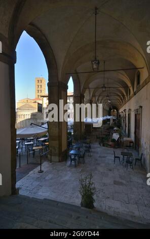 Vasari Lodges, Logge Vasari, früh am Morgen mit leeren Restauranttischen mit Pieve di Santa Maria im Hintergrund Stockfoto