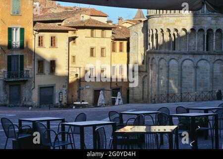 Alte Gebäude auf dem alten Hauptplatz von arezzo mit leeren Restauranttischen in der Morgendämmerung Stockfoto