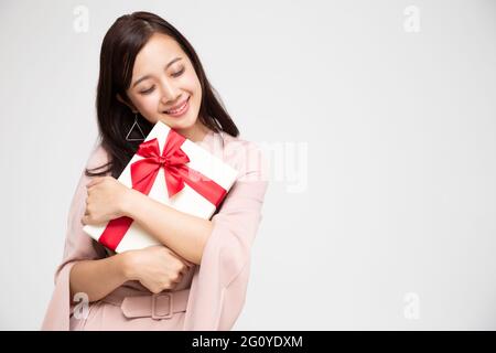 Glücklich schöne asiatische Frau lächeln und umarmt Geschenkbox isoliert auf weißem Hintergrund. Verliebte Mädchen im Teenageralter, die Geschenke von Liebenden erhalten. Neujahr, Chr. Stockfoto