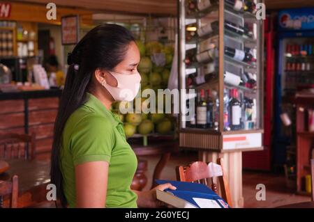 Eine kambodschanische Kellnerin, die eine schützende Gesichtsmaske/Abdeckung trägt, arbeitet während der Coronavirus-Pandemie in Kampong Cham City, Provinz Kampong Cham, Kambodscha, in einem Restaurant. Mai 2020. © Kraig Lieb Stockfoto