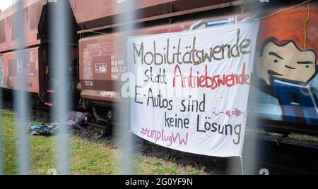 Wolfsburg, Deutschland. Juni 2021. Klimaaktivisten blockieren einen Kohlezug auf dem Gelände des VW-Kohlekraftwerks (fotografiert durch einen Zaun). Seit dem frühen Morgen besetzen Demonstranten der Aktionsgruppe "Get off the Gas" das Kohlekraftwerk im Volkswagen-Werk in Wolfsburg. Quelle: Julian Stratenschulte/dpa/Alamy Live News Stockfoto