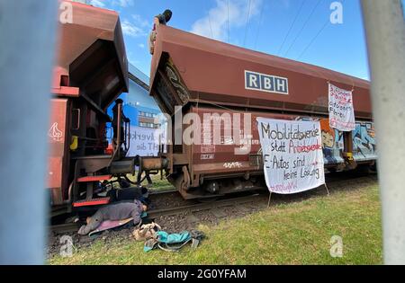 Wolfsburg, Deutschland. Juni 2021. Klimaaktivisten blockieren einen Kohlezug auf dem Gelände des VW-Kohlekraftwerks (fotografiert durch einen Zaun). Seit dem frühen Morgen besetzen Demonstranten der Aktionsgruppe "Get off the Gas" das Kohlekraftwerk im Volkswagen-Werk in Wolfsburg. Quelle: Julian Stratenschulte/dpa/Alamy Live News Stockfoto