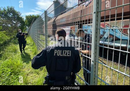 Wolfsburg, Deutschland. Juni 2021. Polizeibeamte stehen neben einem Kohlezug, der von Aktivisten besetzt ist, auf dem Gelände des VW-Kohlekraftwerks. Demonstranten der Aktionsgruppe "get off the Gas" besetzen seit heute früh das Kohlekraftwerk im Volkswagen-Werk in Wolfsburg. Quelle: Julian Stratenschulte/dpa/Alamy Live News Stockfoto