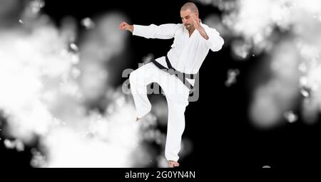 Komposition eines kaukasischen männlichen Karate-Kämpfers auf schwarzem Hintergrund mit weißer Unschärfe Stockfoto