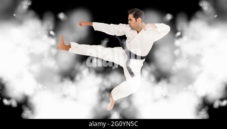 Komposition eines kaukasischen männlichen Karate-Kämpfers auf schwarzem Hintergrund mit weißer Unschärfe Stockfoto