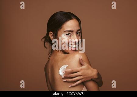 Nahaufnahme einer lächelnden jungen Frau mit Vitiligo im Gesicht. Seitenansicht Porträt einer Frau mit Schönheitscreme auf dem Rücken. Stockfoto