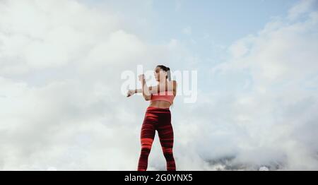 Weibliche Sportlerin in Sportbekleidung macht Aufwärmübungen. Sportlerin beim Stretching im Freien. Stockfoto