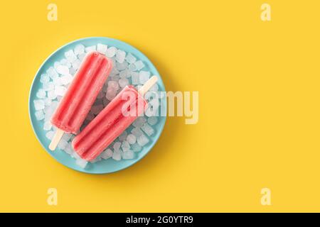 Erdbeerpopsicles mit Eis auf gelbem Hintergrund Stockfoto