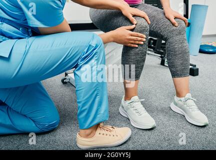 Osteopath, der eine Kniediagnostik einer Frau in einem Rehabilitationszentrum macht, Nahaufnahme. Die Patientin mit Knieverletzung besucht ihren Physiotherapeuten Stockfoto