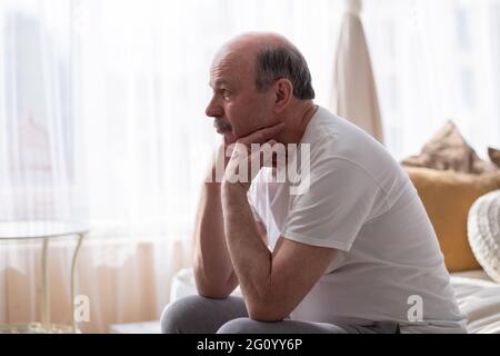 Traurig, älterer Mann mit dem Kopf in den Händen auf dem Bett zu Hause sitzen Stockfoto