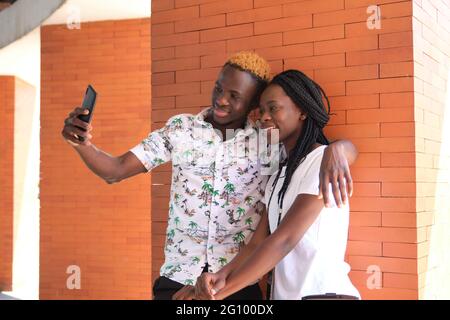 Junges glückliches afrikanisches Paar, das mit seinem Smartphone ein Selfie macht. Lifestyle-Konzept. Stockfoto