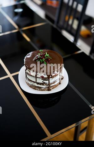 Brownie-Schokoladenkuchen mit Kirschen und Frischkäse, gekrönt mit dunklen Schokoladen-Ganache-Kirschen und Minzblättern Stockfoto